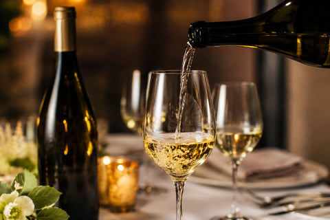 Glass of premium Chardonnay wine being poured beside a bottle on an elegant table