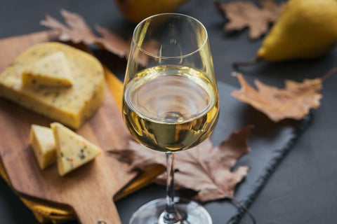 Glass of Chenin Blanc beside cheese, pears, and autumn leaves, representing premium white wine sourcing for a wine program